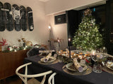 Candlelit Christmas dining table with greenery and a decorated tree