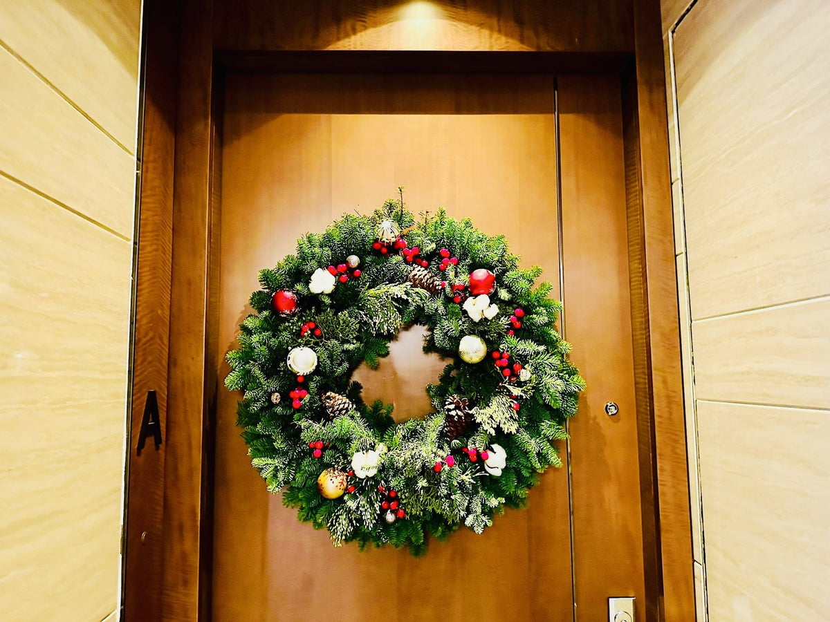Fresh Christmas wreath with red berries, pine cones and ornaments on a wooden door